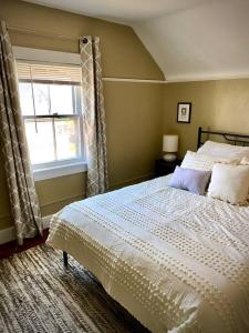 Un dormitorio con una cama blanca con una ventana. en Artist retreat near all Rochester sites, en Rochester
