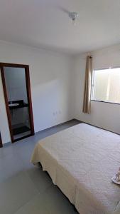 Habitación blanca con cama y espejo en Apartamento Praia Taperapuan, en Porto Seguro