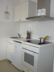 a white kitchen with a sink and a stove at Heidelandhaus Zühlke mit gemütlicher Südterrasse in Soltau