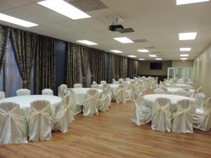 a room full of tables and chairs with white bows at Airport Inn in Nederland +63 photos