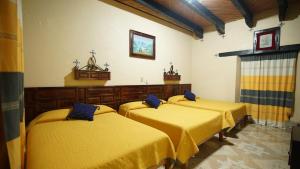 three beds in a room with yellow sheets at Hotel Palacio de Moctezuma in San Cristóbal de Las Casas