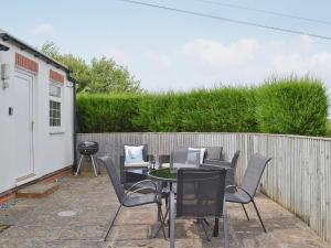 un patio con mesa, sillas y una valla en Magpie Cottage en Gristhorpe