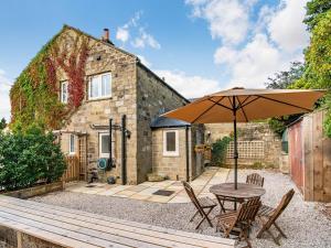 a table with an umbrella in front of a cottage at Kiln Hill Cottage in Pateley Bridge