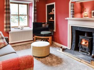un soggiorno con pareti rosse e camino di Oakwood Cottage a Glencoe