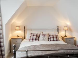 a bedroom with a bed with pillows and two lamps at Raglan Cottage in Ardentinny