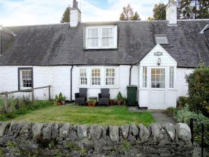 Raglan Cottage في Ardentinny: منزل أبيض مع كرسيين في ساحة