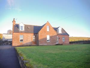 a large brick house with a grass field in front of it at Liftingstane Farmhouse in Closeburn