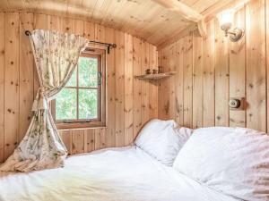 een slaapkamer met houten wanden en een bed met een raam bij The Kingfisher - Uk40298 in Martin