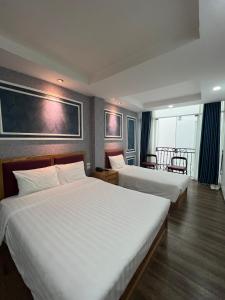 ein Hotelzimmer mit 2 Betten mit weißer Bettwäsche in der Unterkunft Holiday Suites Hotel & Spa in Hanoi