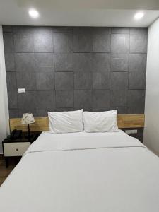 Holiday Suites Hotel & Spa في هانوي: غرفة نوم بسرير ابيض وجدار رمادي