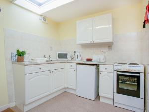 cocina blanca con electrodomésticos blancos y ventana en Apartment Fourteen - Uk39870, en Paignton