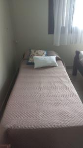 Una cama en un dormitorio con una almohada. en Chalet del Rosedal en San Salvador de Jujuy