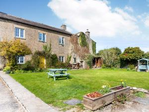 an old stone house with a picnic table in the yard at The Farmhouse - Uk33419 in West Witton