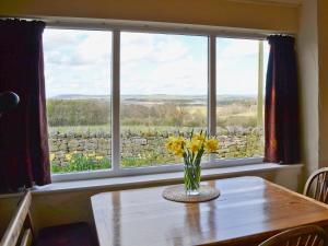 a vase of flowers on a table in front of a window at Garden Cottage in Edlingham
