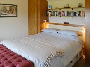 a bedroom with a white bed with a red ottoman at Garden Cottage in Edlingham