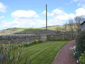 a stone wall next to a yard with a field at Garden Cottage in Edlingham