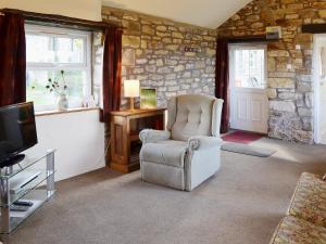 a living room with a chair and a television at Garden Cottage in Edlingham