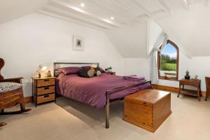 a bedroom with a purple bed and a window at Trellys Hyfryd - cottage in Fishguard