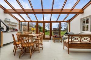 a conservatory with a table and chairs and a glass ceiling at Trellys Hyfryd - cottage in Fishguard