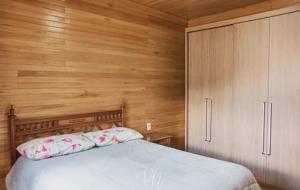 sypialnia z łóżkiem i drewnianą ścianą w obiekcie Casa do Guiga w mieście São Joaquim
