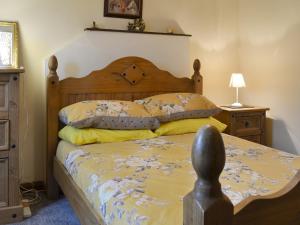 a bedroom with a wooden bed with yellow pillows at Rallt Fawr in Gwalchmai