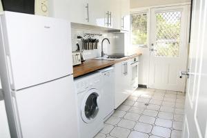 a white kitchen with a washing machine and a sink at Bundeena Base Art House in Bundeena