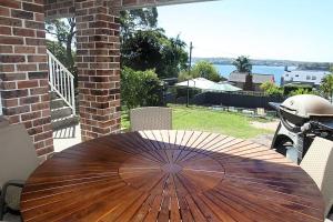 a wooden table with an umbrella on a patio at Bundeena Base Art House in Bundeena