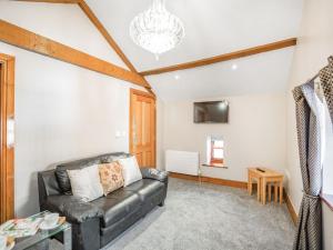 a living room with a leather couch and a tv at Corby Castle - Diamond Cottage - Uk34668 in Great Corby
