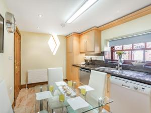 cocina con mesa de cristal y electrodomésticos blancos en Corby Castle - Diamond Cottage - Uk34668, en Great Corby