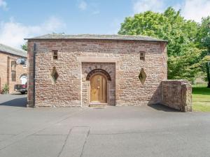 a brick building with a wooden door on a street at Corby Castle - Diamond Cottage - Uk34668 in Great Corby