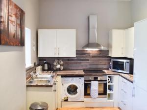 a kitchen with a washing machine and a microwave at Beckside House in Dalton in Furness