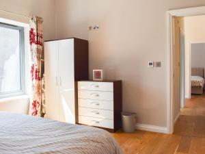 a bedroom with a bed and a dresser and a window at Beckside House in Dalton in Furness