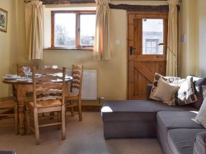 a living room with a table and a couch at Oak Barn Cottage in Trefonen