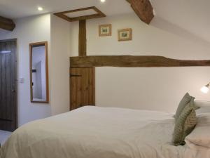 a bedroom with a large white bed with wooden beams at Oak Barn Cottage in Trefonen