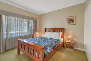 a bedroom with a bed and a window at Aisling Cottage in Port Fairy