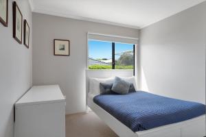 a white bedroom with a bed and a window at Birdland in Port Fairy