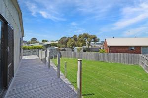a wooden walkway next to a house with a yard at Birdland in Port Fairy