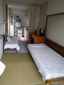 a small room with two beds and a kitchen at Minshuku Zabaru in Ishigaki Island