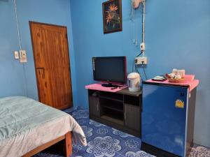 a room with a tv on a desk with a bed at หอพักโชคอนันต์ in Chiang Rai