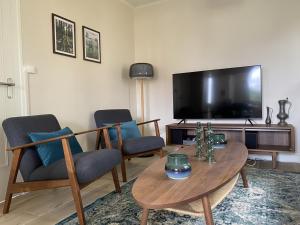salon ze stołem i krzesłami oraz telewizorem z płaskim ekranem w obiekcie Magnifique T3 au centre, jardin privatif, proche thermes, wifi, parking, jeux extérieurs, lave-linge/sèche-linge - FR-1-541-94 w mieście La Roche-Posay