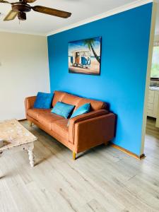 a brown couch in a living room with a blue wall at Decades in Port Willunga