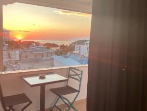 stół i krzesła na balkonie z widokiem na zachód słońca w obiekcie Villa White w mieście Ksamil