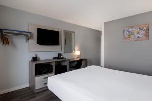 um quarto com uma cama branca e uma televisão em Econo Lodge Scottsbluff em Scottsbluff