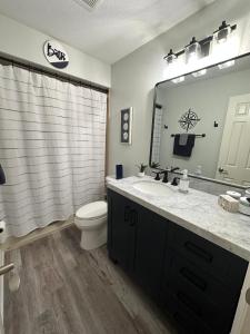 W łazience znajduje się umywalka, toaleta i lustro. w obiekcie Three Treasures Beach House w mieście New Smyrna Beach
