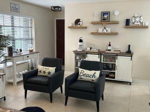 a living room with two chairs and a table at Three Treasures Beach House in New Smyrna Beach