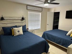 a bedroom with two beds with blue sheets and a fan at Three Treasures Beach House in New Smyrna Beach
