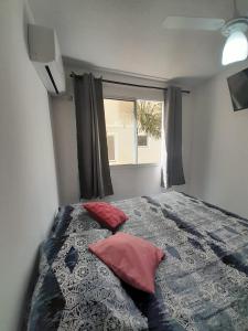 1 dormitorio con 1 cama con 2 almohadas y ventana en APTO - 2 quartos com ar condicionado - piscina disponível, en Campo Grande