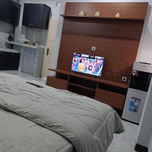 Dormitorio con cama y tocador con TV en Anyak's place Syariah en Yogyakarta