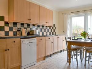 a kitchen with a table and a white dishwasher at The Larches in Aspatria