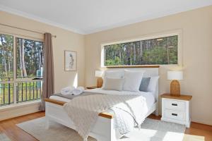 a white bedroom with a bed and a window at Tall Trees- Forest hideaway on Hastings Lagoon in Hastings